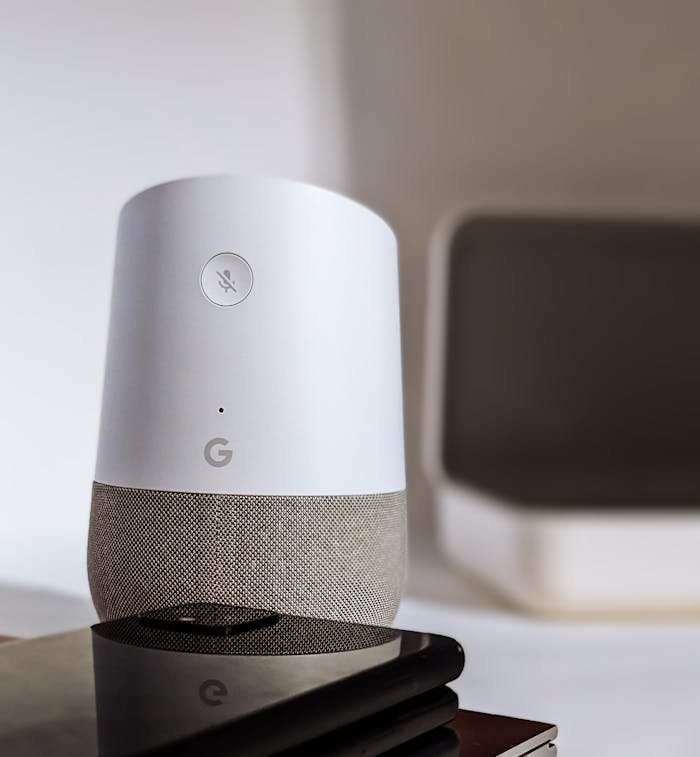 A sleek smart speaker and smartphone displayed on a table indoors, highlighting modern technology.